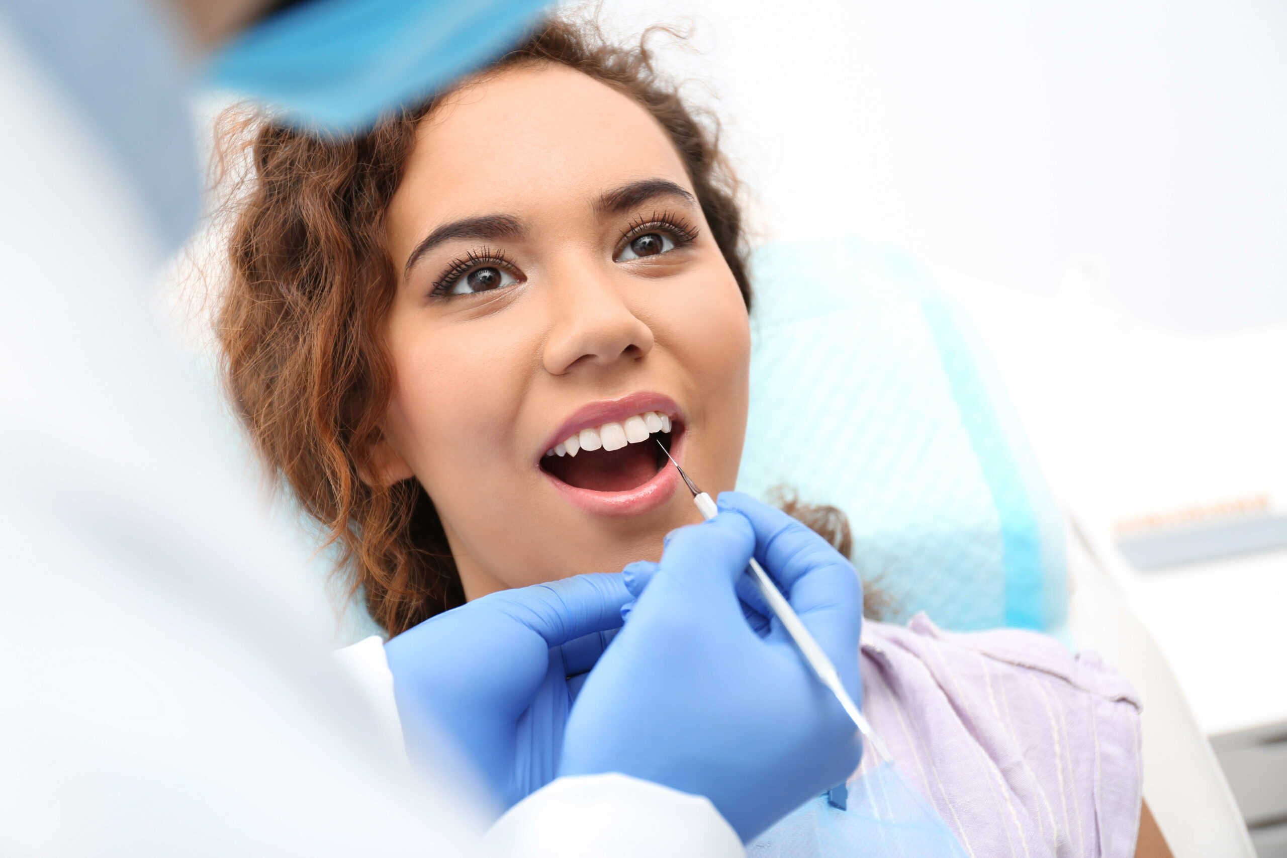 Dentist examining African-American woman's teeth with probe in hospital in Warren, MI
